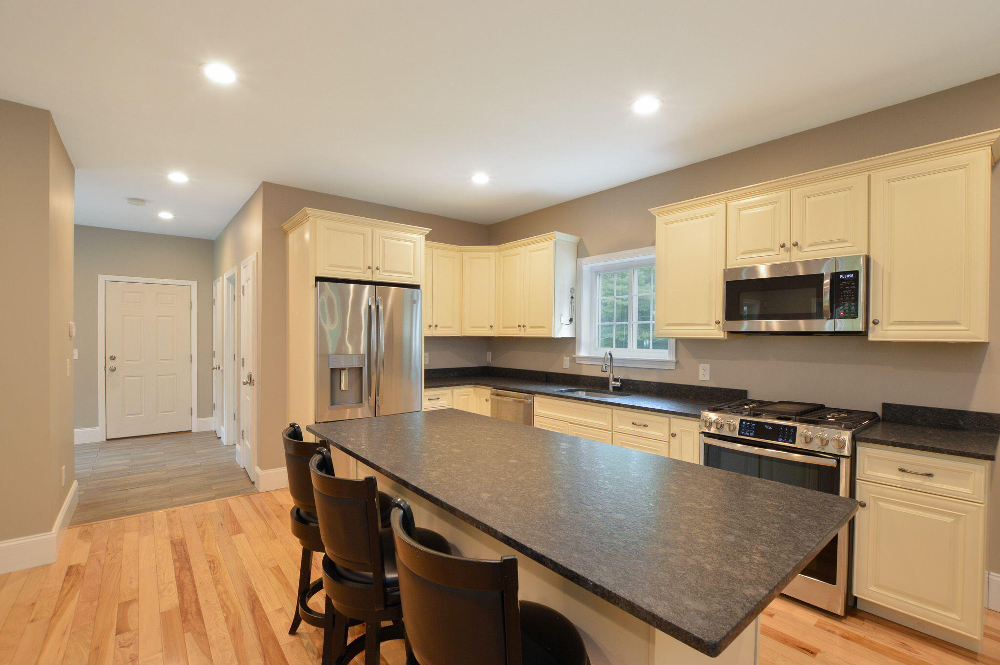 828 Cotuit Road Mashpee, MA 02649 - Photo 9 of 41 a kitchen with stainless steel appliances granite countertop a stove a refrigerator a microwave a sink and white cabinets with wooden floor