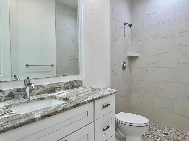 a bathroom with a granite countertop sink a toilet and a mirror