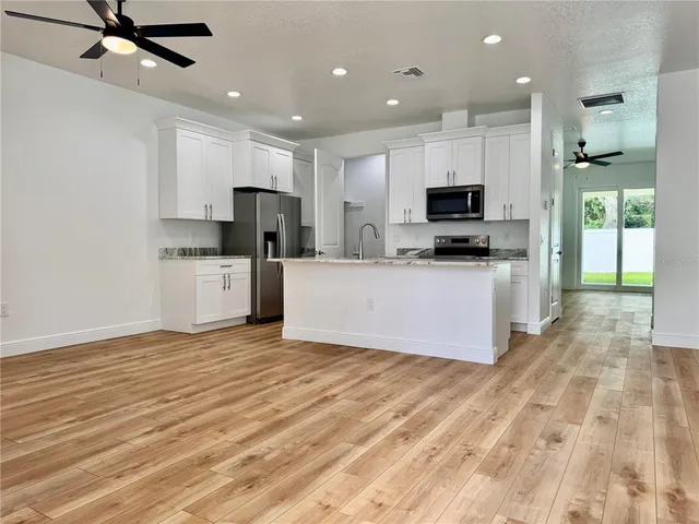 a kitchen with stainless steel appliances kitchen island granite countertop a stove top oven a sink and a granite counter top