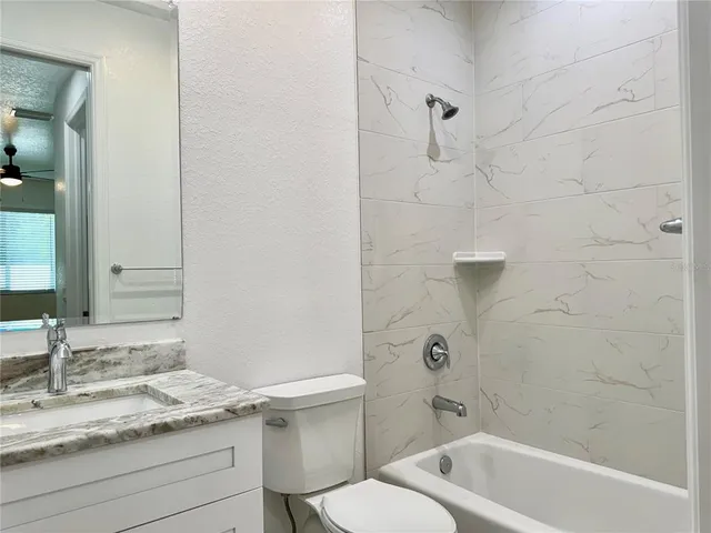 a bathroom with a granite countertop sink a toilet and shower