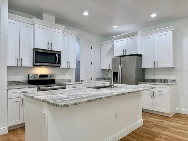 a kitchen with stainless steel appliances granite countertop a stove a sink a refrigerator a microwave and cabinets