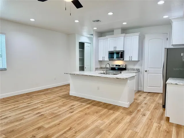 a large kitchen with stainless steel appliances granite countertop a stove a sink and a refrigerator