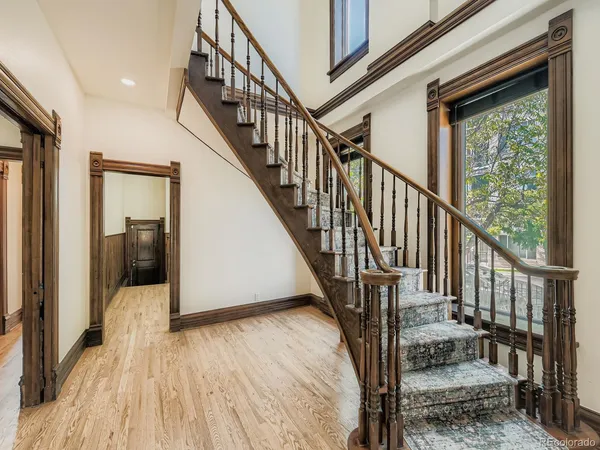 a view of a hallway with wooden floor staircase and a bathroom