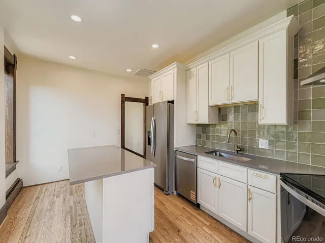 a kitchen with stainless steel appliances granite countertop a refrigerator sink and white cabinets