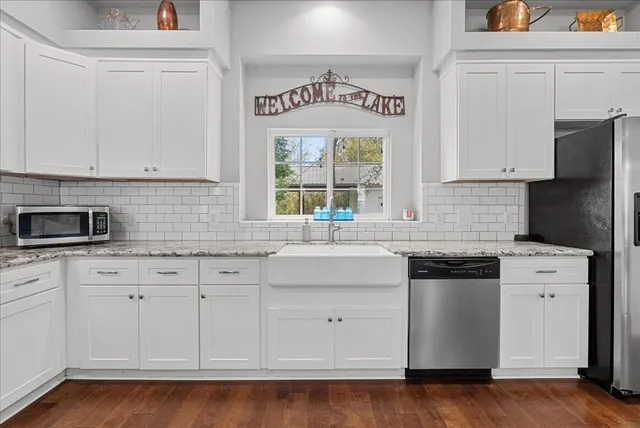 a kitchen with granite countertop white cabinets and a stove with wooden floor