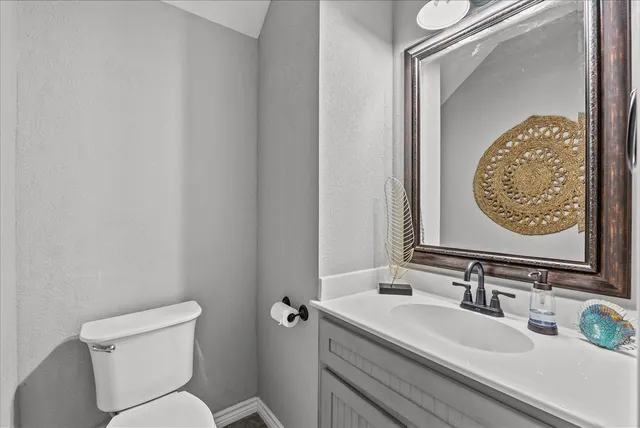 a bathroom with a granite countertop sink mirror vanity and toilet