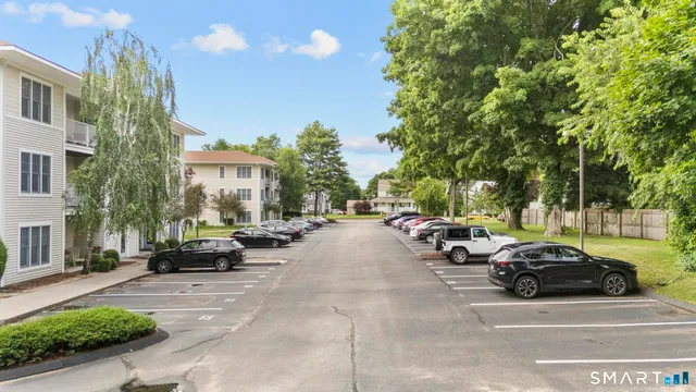 a view of road with card parked on side and retail shops