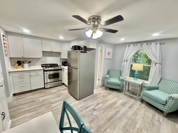 a kitchen with a refrigerator a sink dishwasher a dining table and chairs with wooden floor