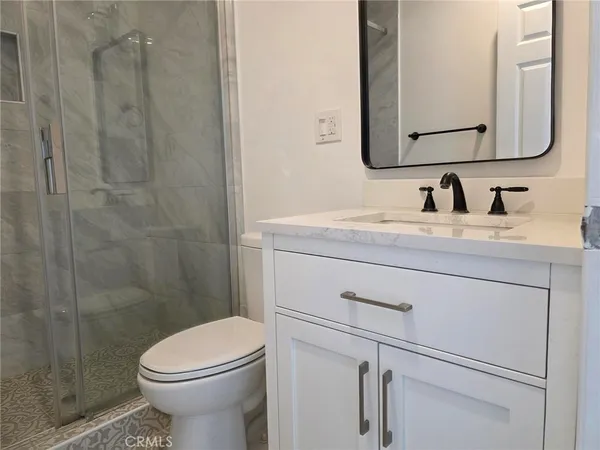 a bathroom with a granite countertop sink mirror vanity and toilet
