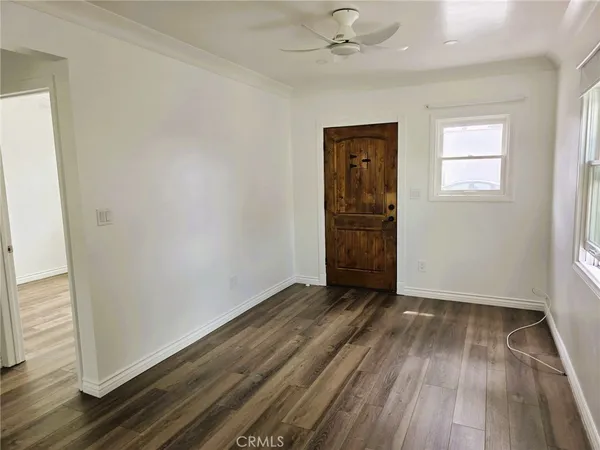an empty room with wooden floor closet and windows