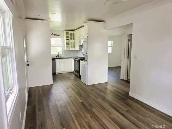 a view of a kitchen with refrigerator and wooden floor