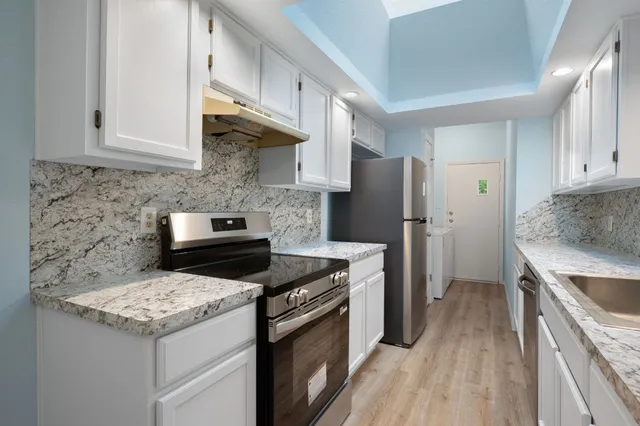 a kitchen with granite countertop a sink stove and refrigerator