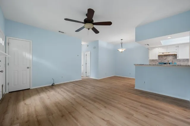 a view of empty room with wooden floor and ceiling fan
