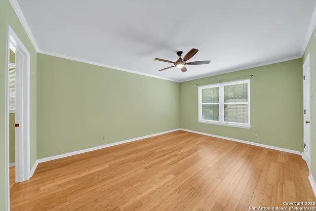 a view of empty room with wooden floor and fan