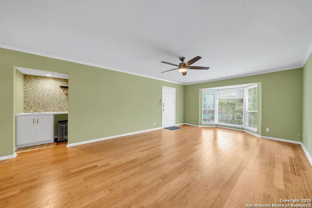 a view of an empty room with window and wooden floor
