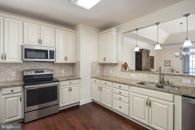 a kitchen with granite countertop white cabinets white stainless steel appliances and a sink