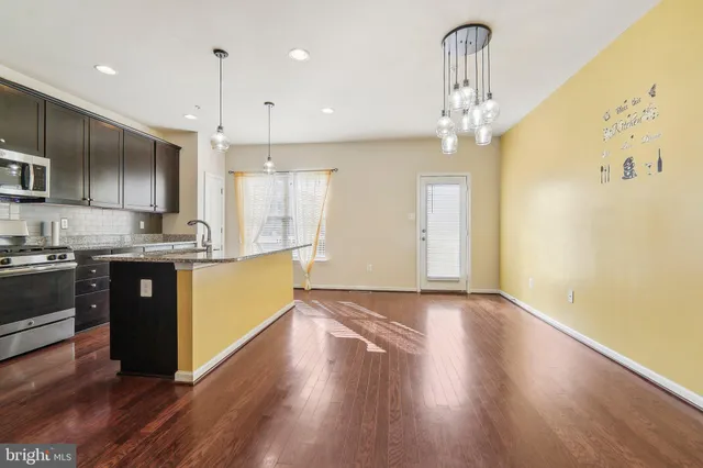 a large kitchen with a center island wooden floor stainless steel appliances and cabinets