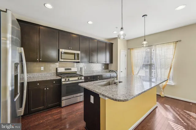 a kitchen with kitchen island granite countertop a sink a counter top space appliances and cabinets