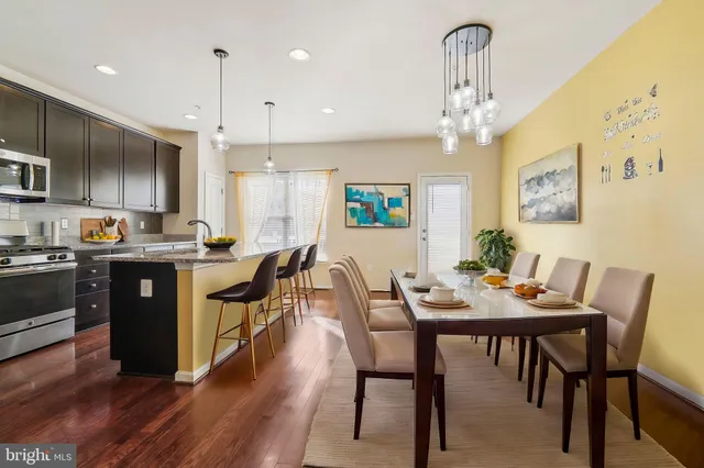 a kitchen with stainless steel appliances kitchen island granite countertop a table chairs and a refrigerator