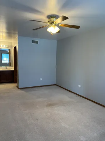 a view of an empty room and chandelier fan