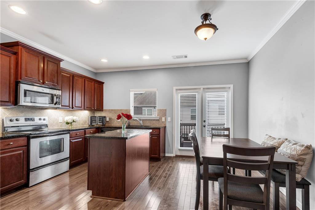 3039 Liberty Way Northwest Atlanta, GA 30318 - Photo 10 of 43 a kitchen with stainless steel appliances granite countertop a stove top oven a sink dishwasher a dining table and chairs with wooden floor