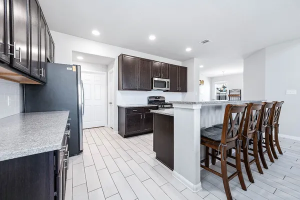 a kitchen with stainless steel appliances kitchen island granite countertop a refrigerator and microwave
