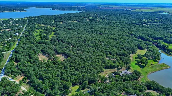 an aerial view of a houses with a yard and lake view