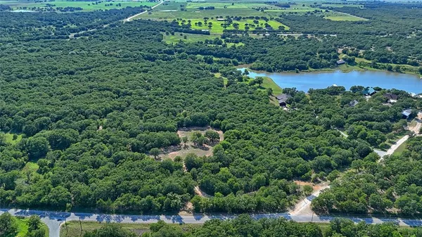an aerial view of residential house with outdoor space and trees all around
