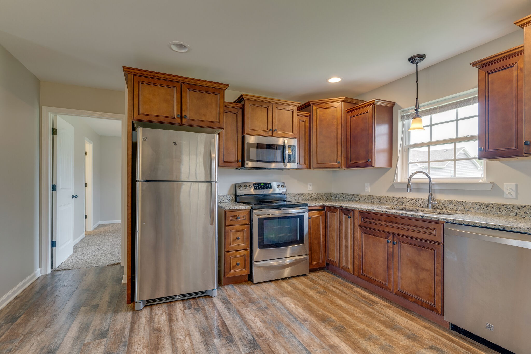 202 Shaub Road Portland, TN 37148 - Photo 7 of 25 a kitchen with granite countertop wooden floors stainless steel appliances a sink and a window