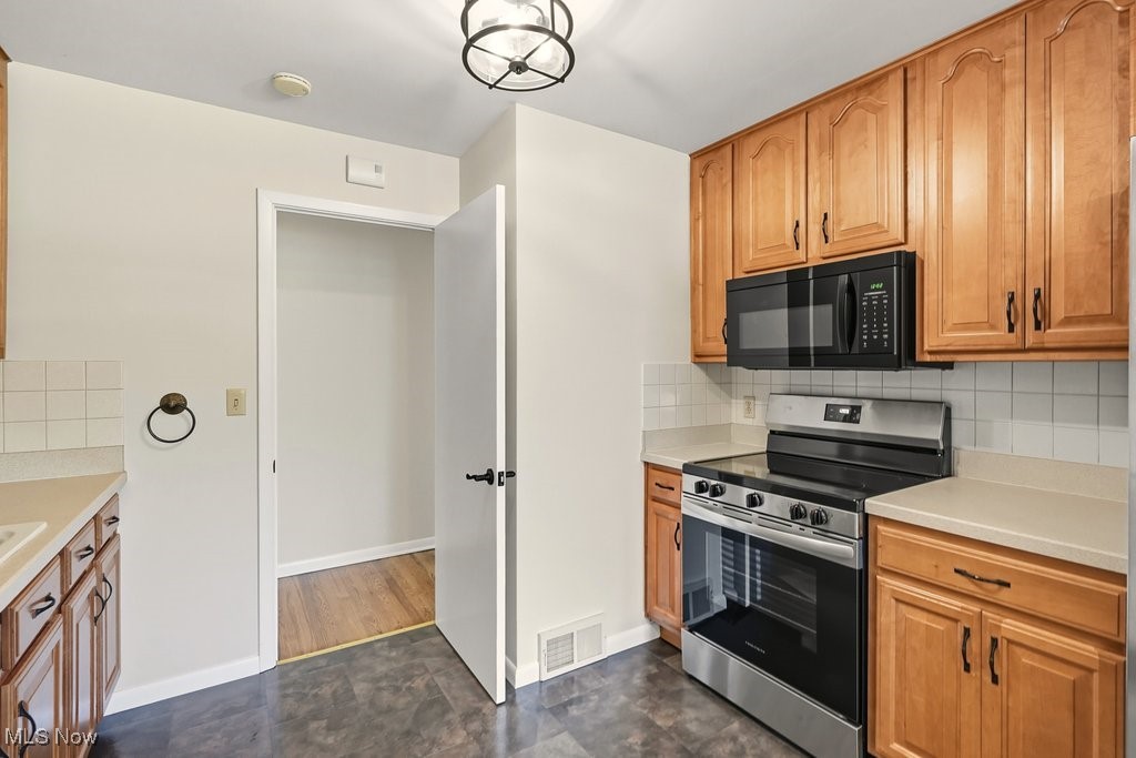 181 Boston Mills Road Hudson, OH 44236 - Photo 20 of 33 Kitchen featuring backsplash, stainless steel electric stove, brown cabinetry, and black microwave