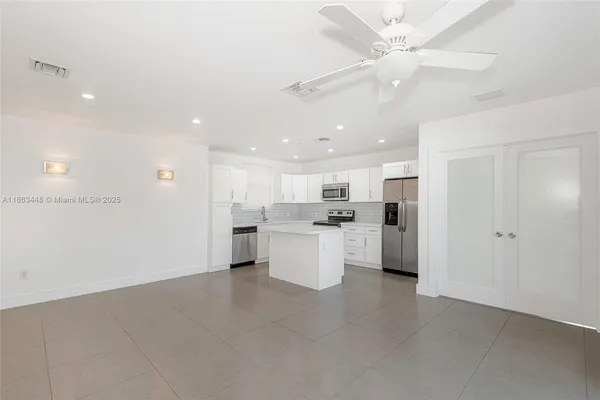 a large kitchen with white cabinets and stainless steel appliances