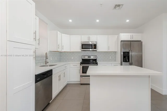 a kitchen with kitchen island a sink stainless steel appliances and cabinets