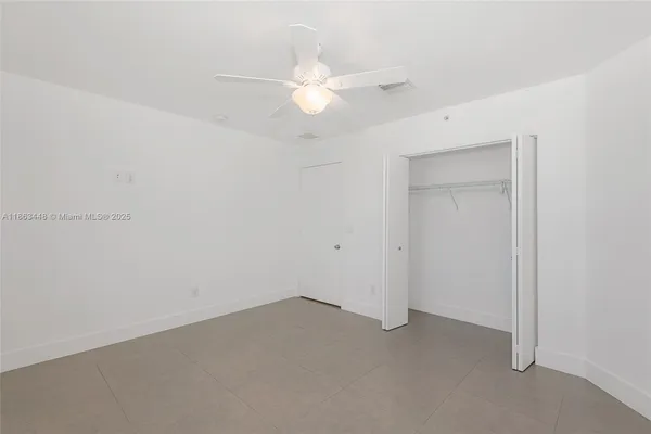 an empty room with a ceiling fan and a window