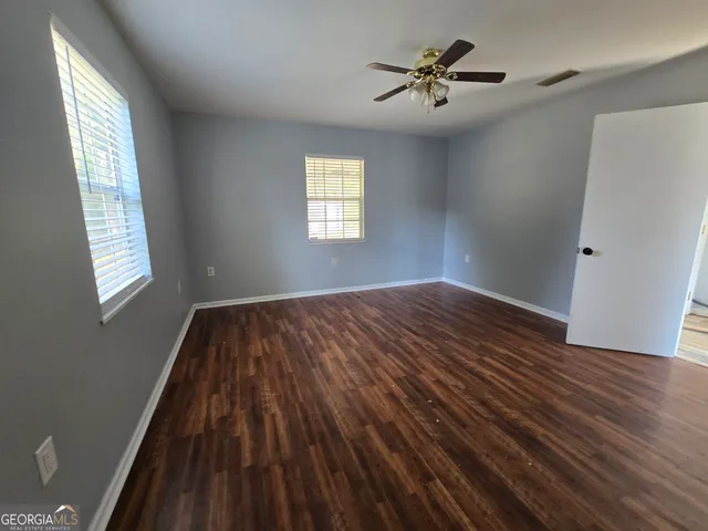 a view of empty room with wooden floor and fan