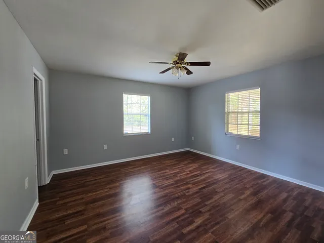 a view of an empty room with a window and wooden floor