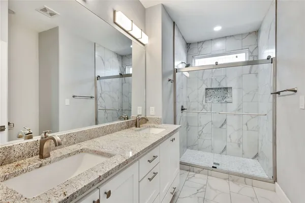 a bathroom with a granite countertop sink mirror and shower
