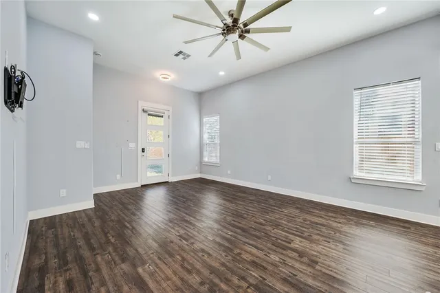 an empty room with wooden floor and windows