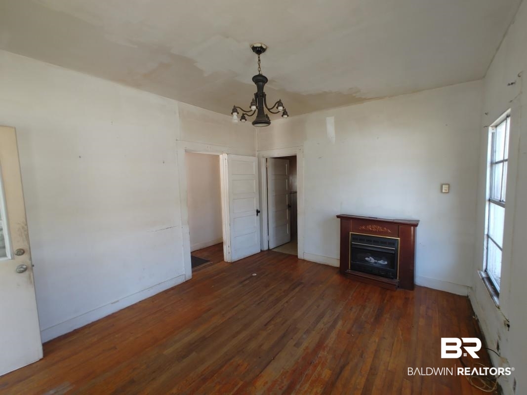 1706 Lomeroy Street Mobile, AL 36604 - Photo 7 of 24 Unfurnished living room with a chandelier, a fireplace, dark wood finished floors, and baseboards
