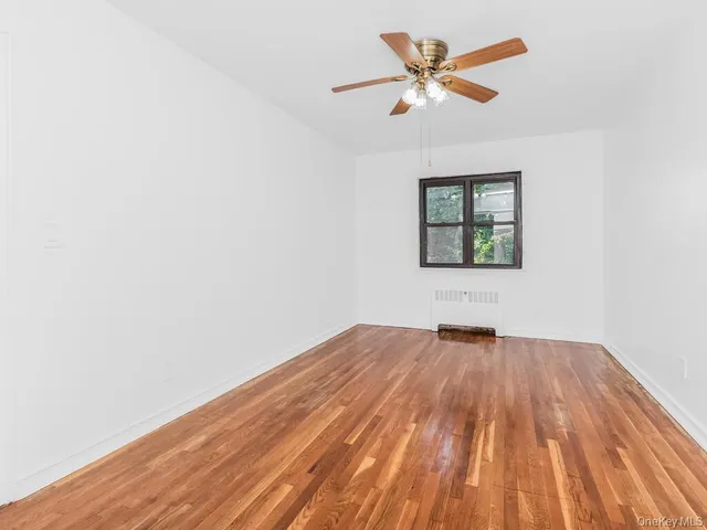 an empty room with wooden floor and ceiling fan