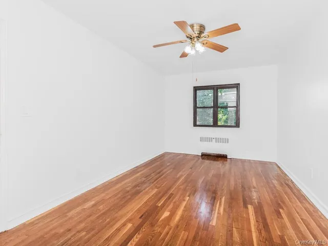 an empty room with wooden floor and ceiling fan