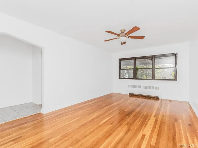 an empty room with wooden floor ceiling fan and windows