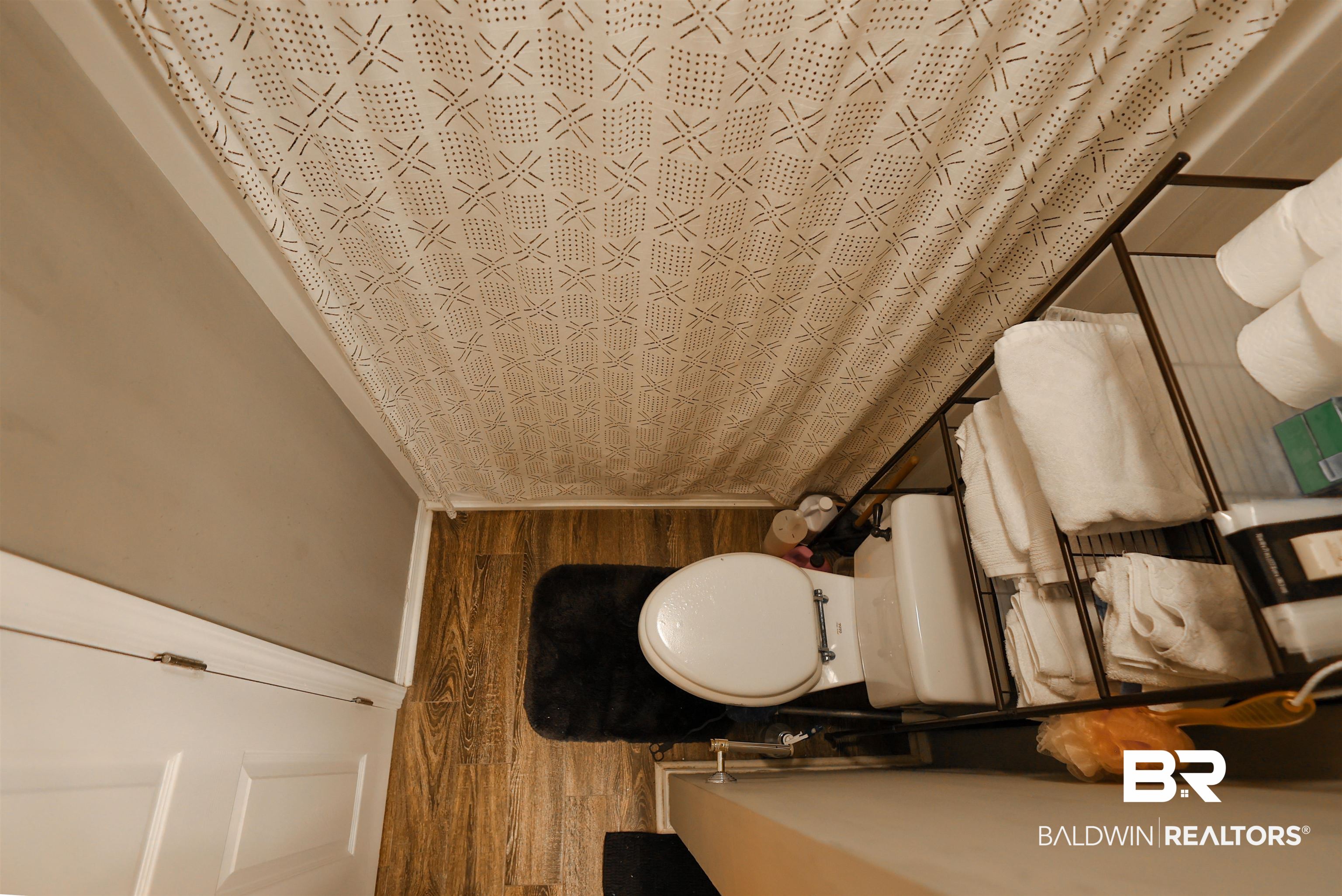 7790 Audubon Drive Foley, AL 36535 - Photo 20 of 39 Bathroom featuring wood-finish flooring, a white toilet, and a built-in metal shelving unit