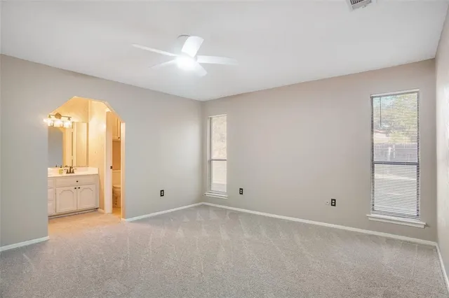 an empty room with windows and fan