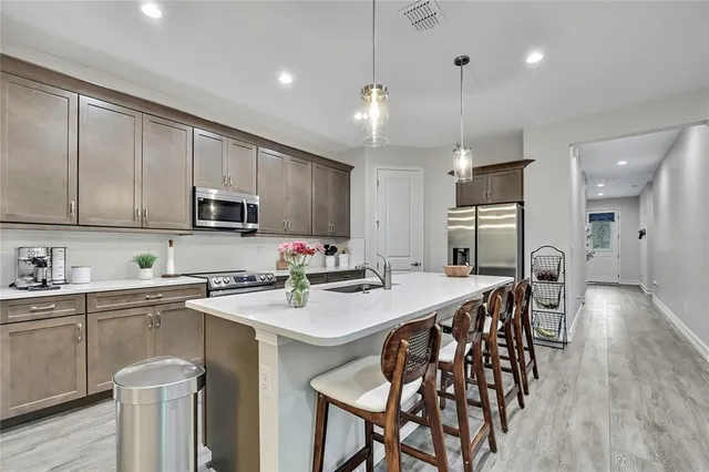 a kitchen with stainless steel appliances a table chairs refrigerator and microwave