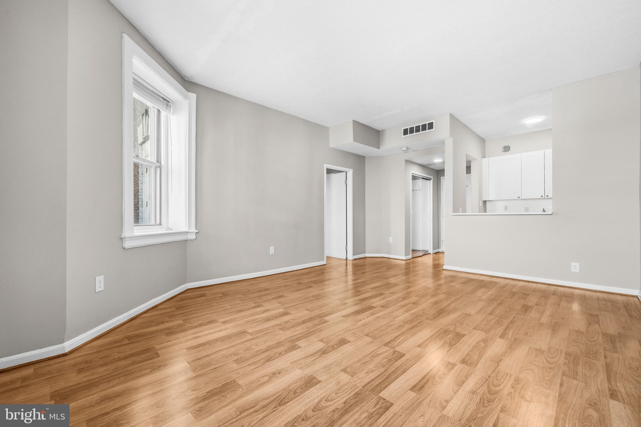 1851 Columbia Road Northwest, Unit 401 Washington, DC 20009 - Photo 6 of 27 a view of an empty room with wooden floor and a window