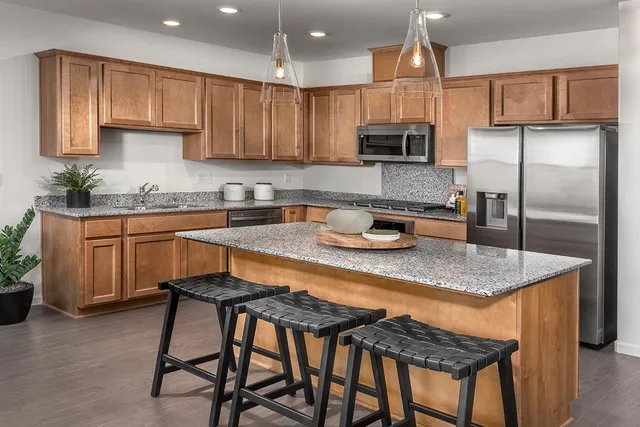 a kitchen with stainless steel appliances granite countertop a refrigerator a sink a stove and cabinets