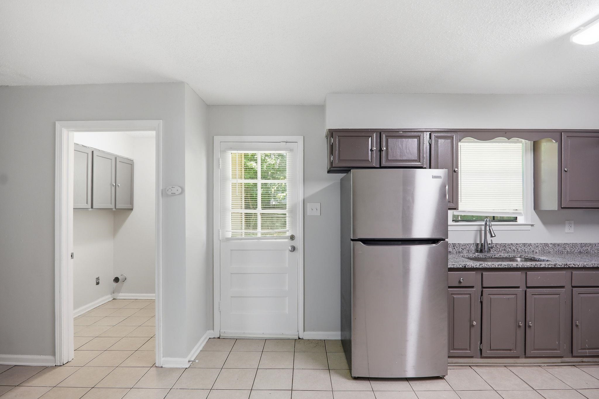 3113 Raleigh Ridge Cove Memphis, TN 38128 - Photo 11 of 38 Kitchen featuring a stainless steel top-freezer refrigerator, dark wood-finish cabinetry, and light-toned countertop
