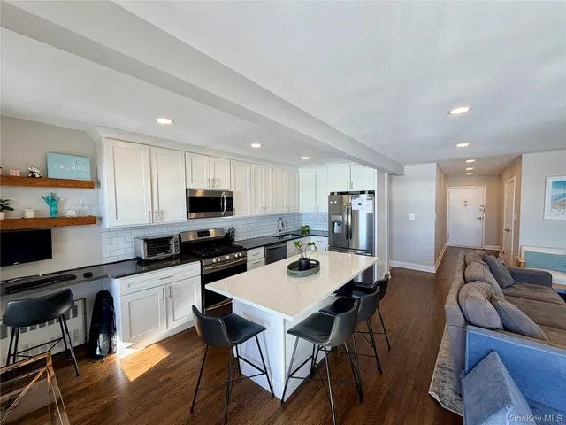 a kitchen with a dining table cabinets appliances and wooden floor