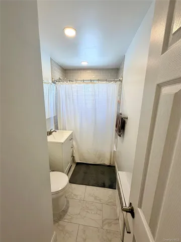 a bathroom with a sink a toilet a window and shower