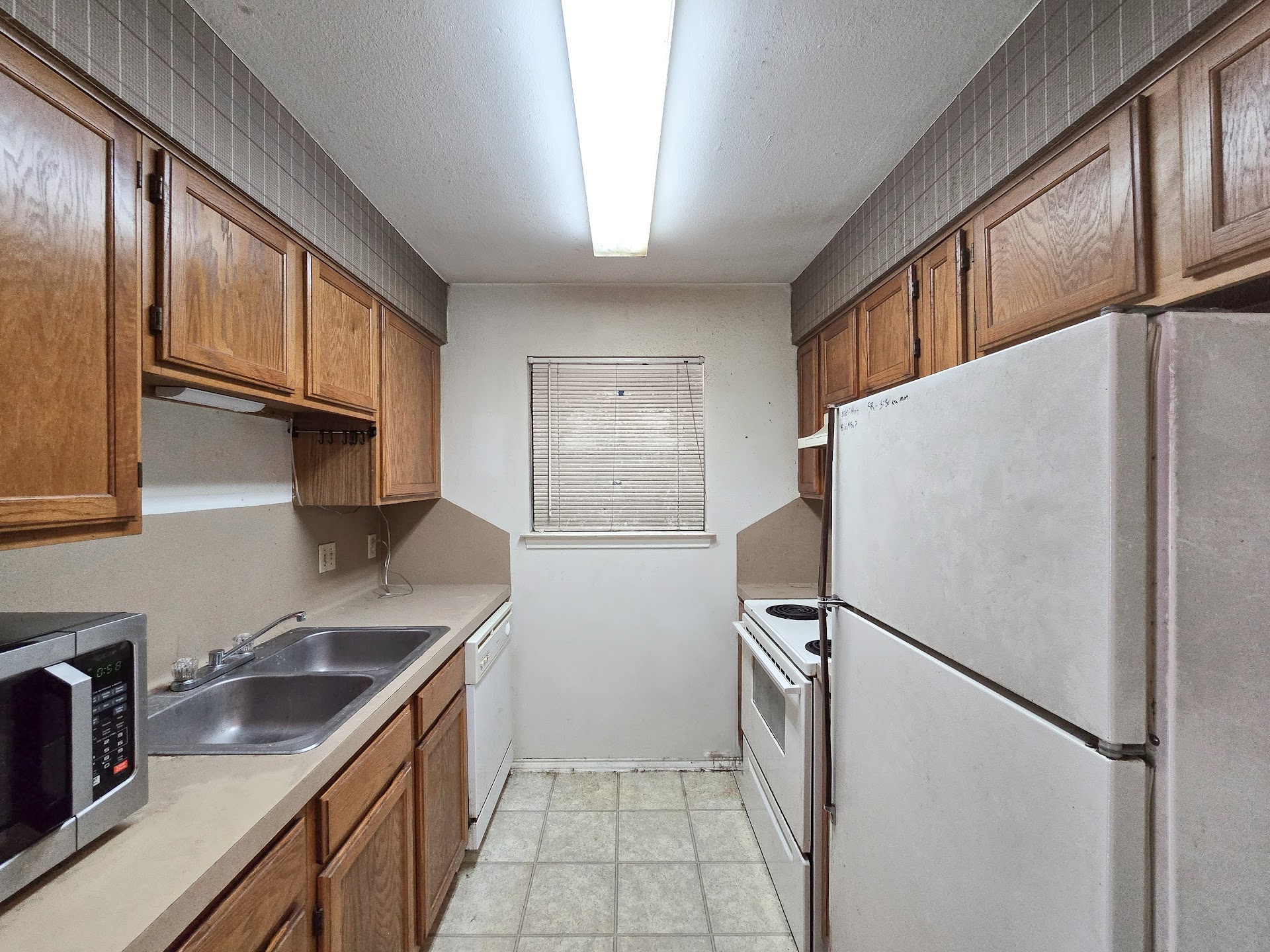 1903 East 20th Street, Unit 202 Austin, TX 78722 - Photo 5 of 8 Kitchen featuring white appliances, a sink, light countertops, brown cabinetry, and baseboards